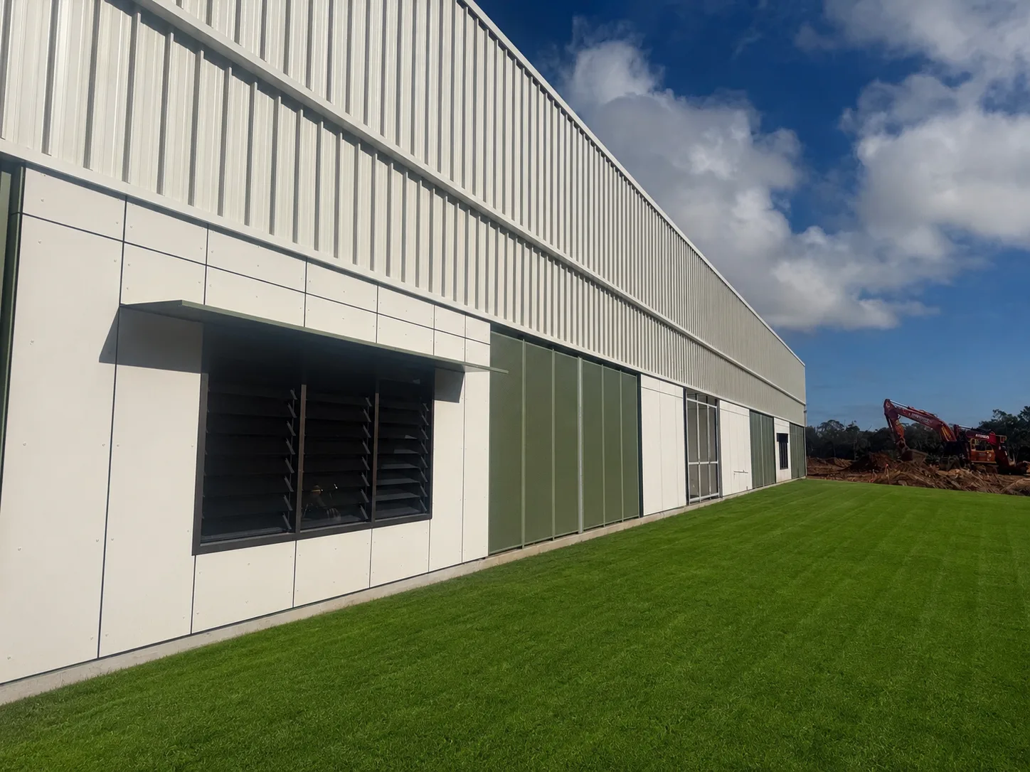 Aluminium sunhood over a louvred window opening on a commercial facade